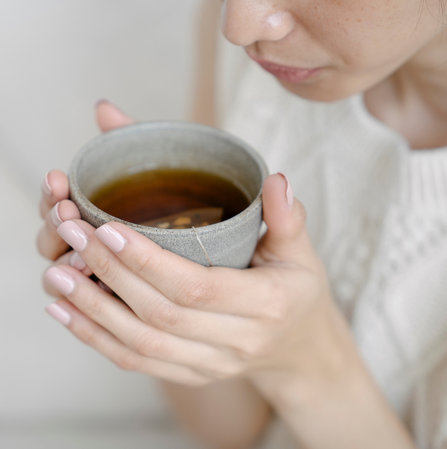 Eine Frau h&auml;lt eine Tasse Tee gegen Heiserkeit